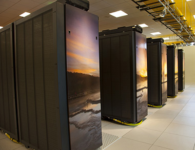 A handful of the Yellowstone supercomputer's 100 racks. An iconic scene from its namesake national park is featured mosaic-style on the ends of each rack. The image by Michael Medford, licensed to National Geographic, centers on Fountain Geyser. (©UCAR. Photo by Carlye Calvin.)